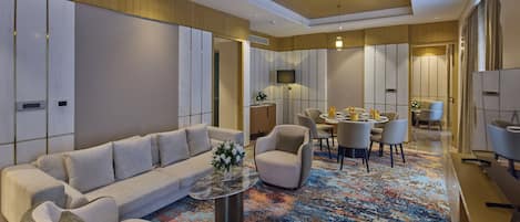 Un moderno vestíbulo de hotel con un sofá, sillones, una mesa de centro, una zona de comedor y un espejo grande.
