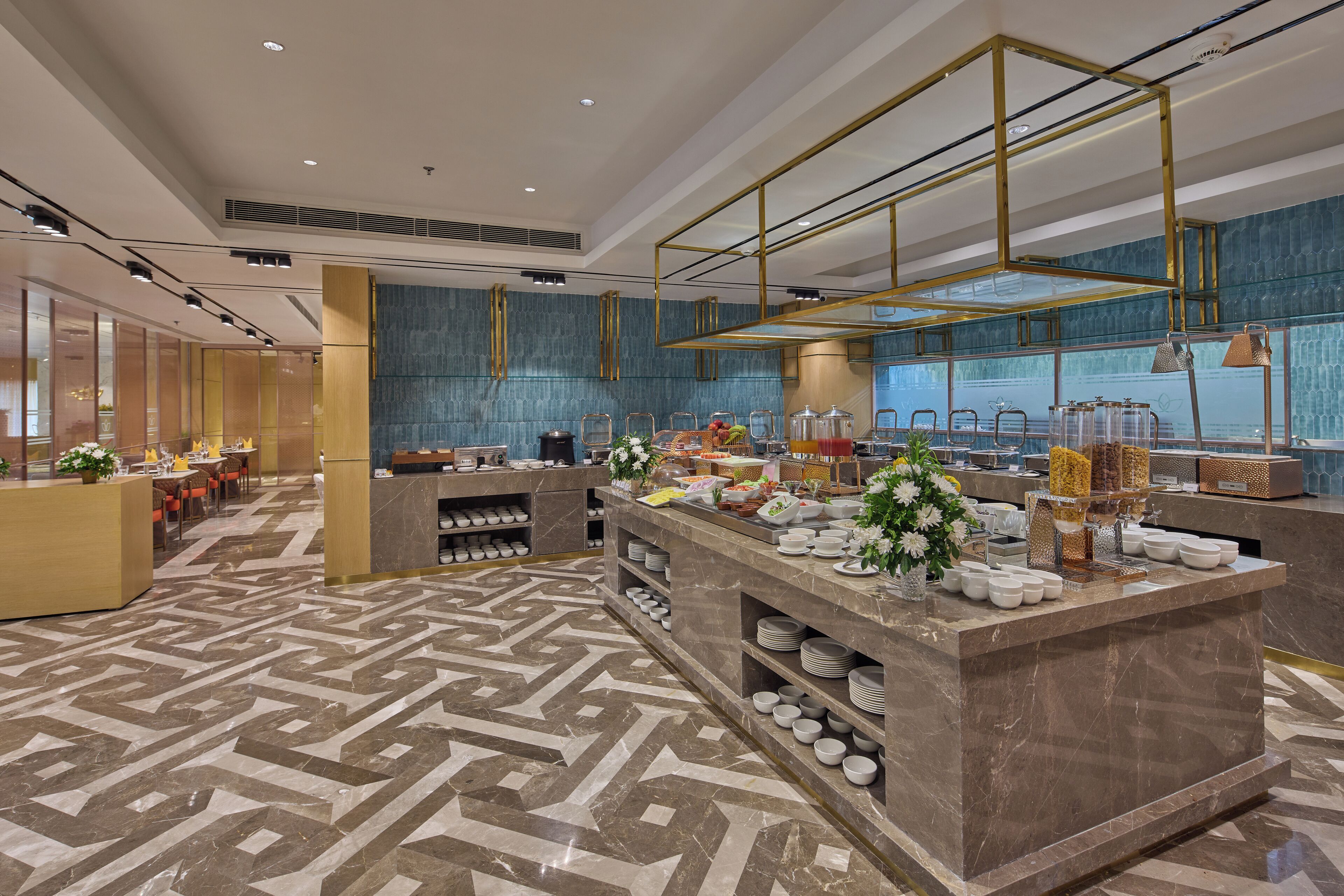 En moderne hotellobby med et centralt barområde, siddepladser og et mønstret gulv.