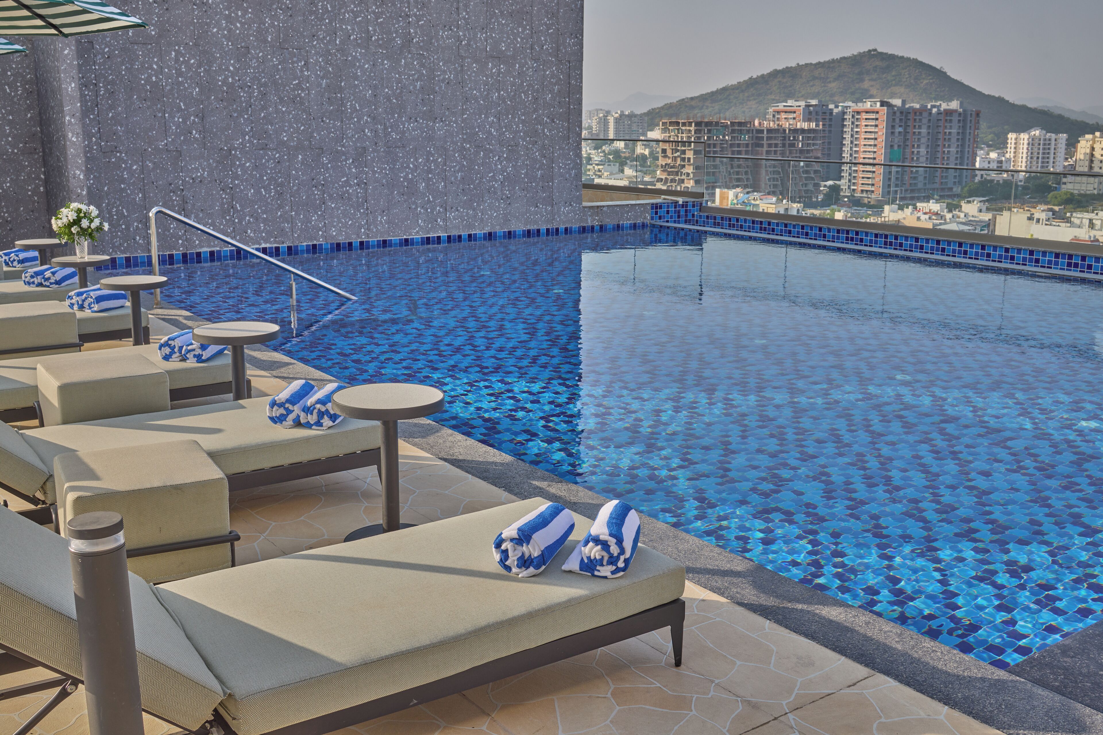 A rooftop pool with lounge chairs and a view of the cityscape.