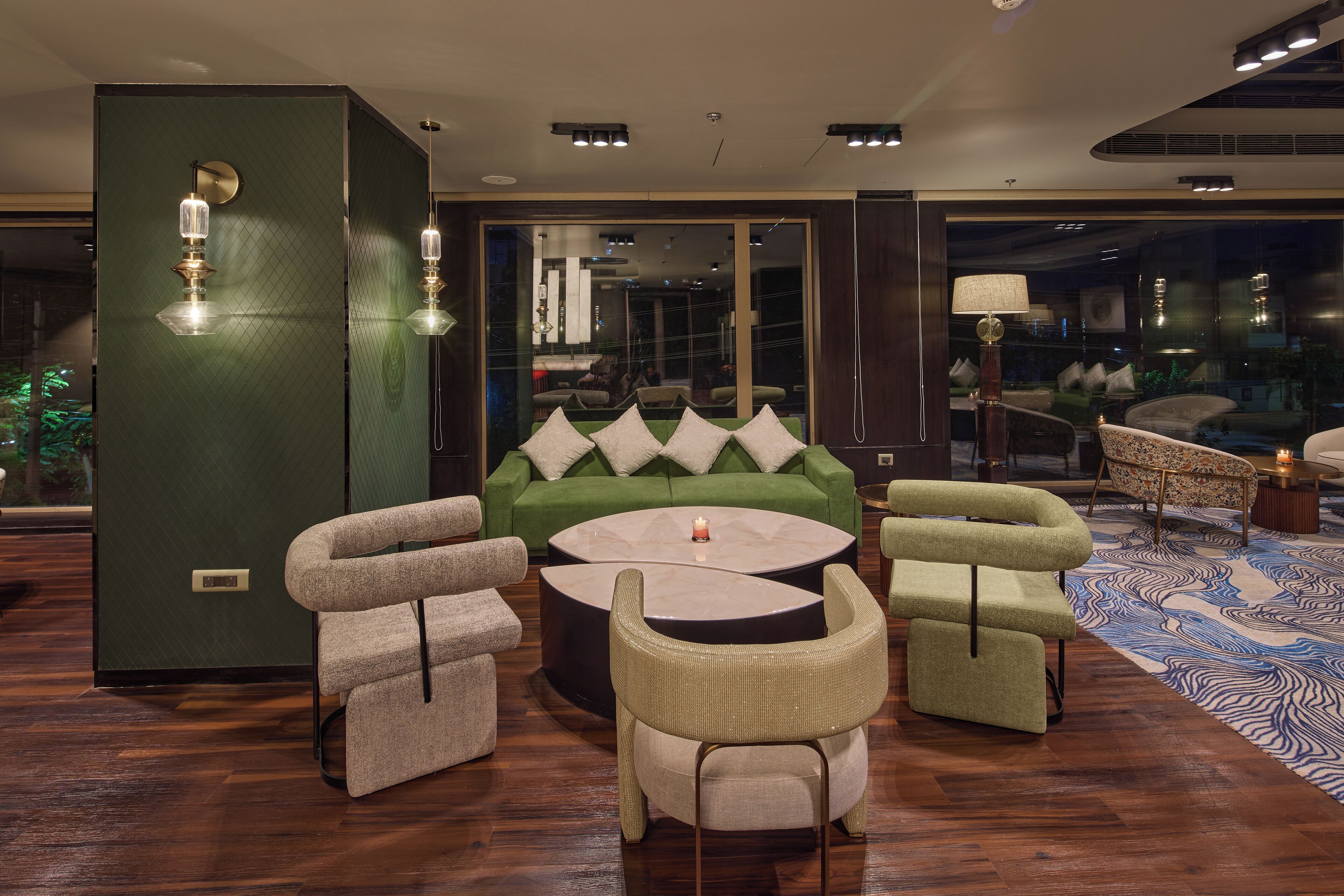 A modern lounge area with a green sofa, two armchairs, and a coffee table.