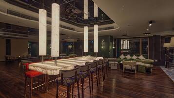A spacious indoor area with a long dining table, multiple chairs, and a seating area with sofas.