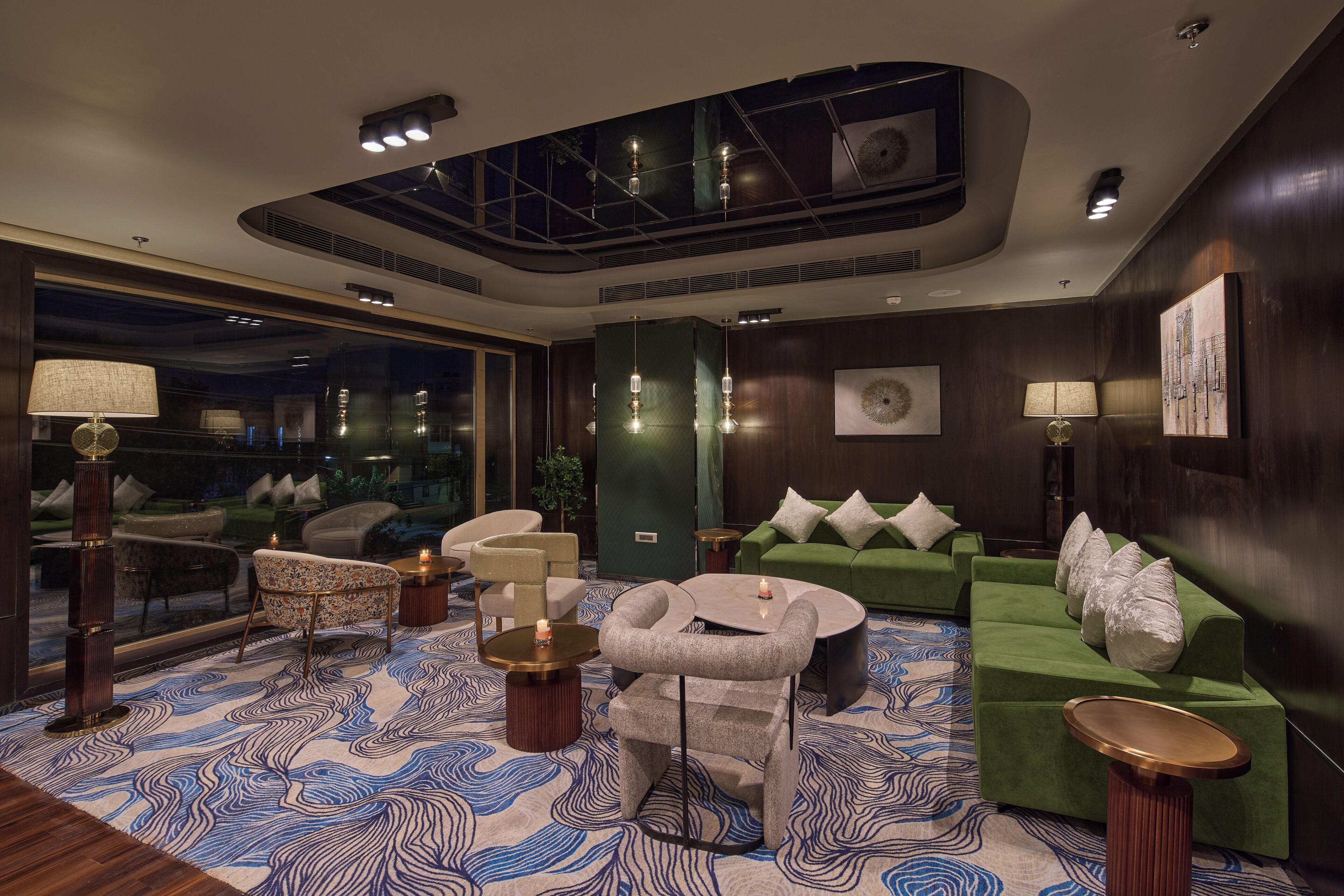 A modern lounge area with a green sofa, a round coffee table, and a patterned rug.