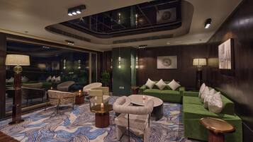A modern lounge area with a green sofa, a round coffee table, and a patterned rug.