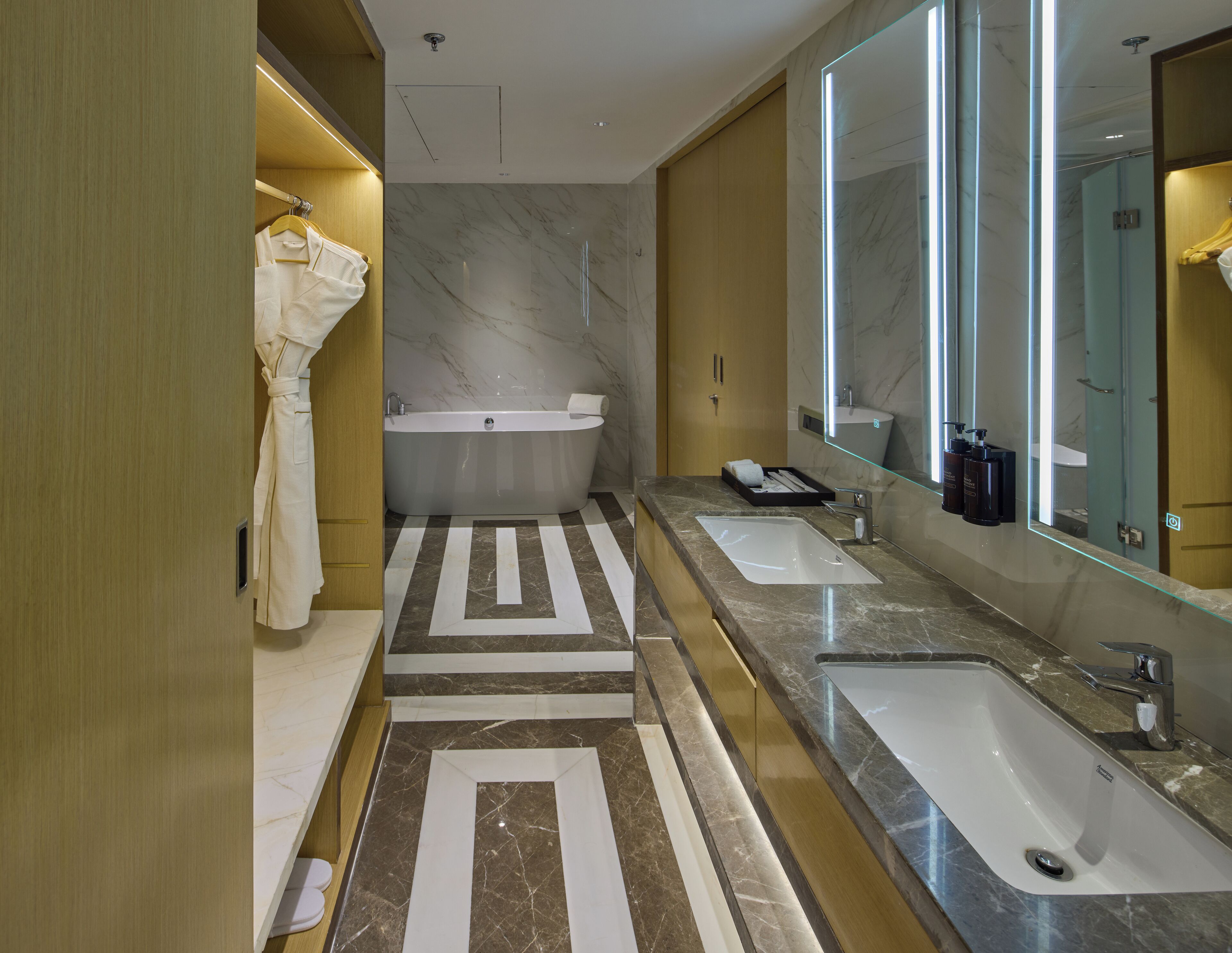 A modern bathroom with a freestanding bathtub, two sinks, and a large mirror.