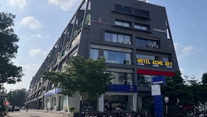 A multi-story building with a sign for "Hotel Acme Sky" and a Tata Motors dealership on the ground floor.