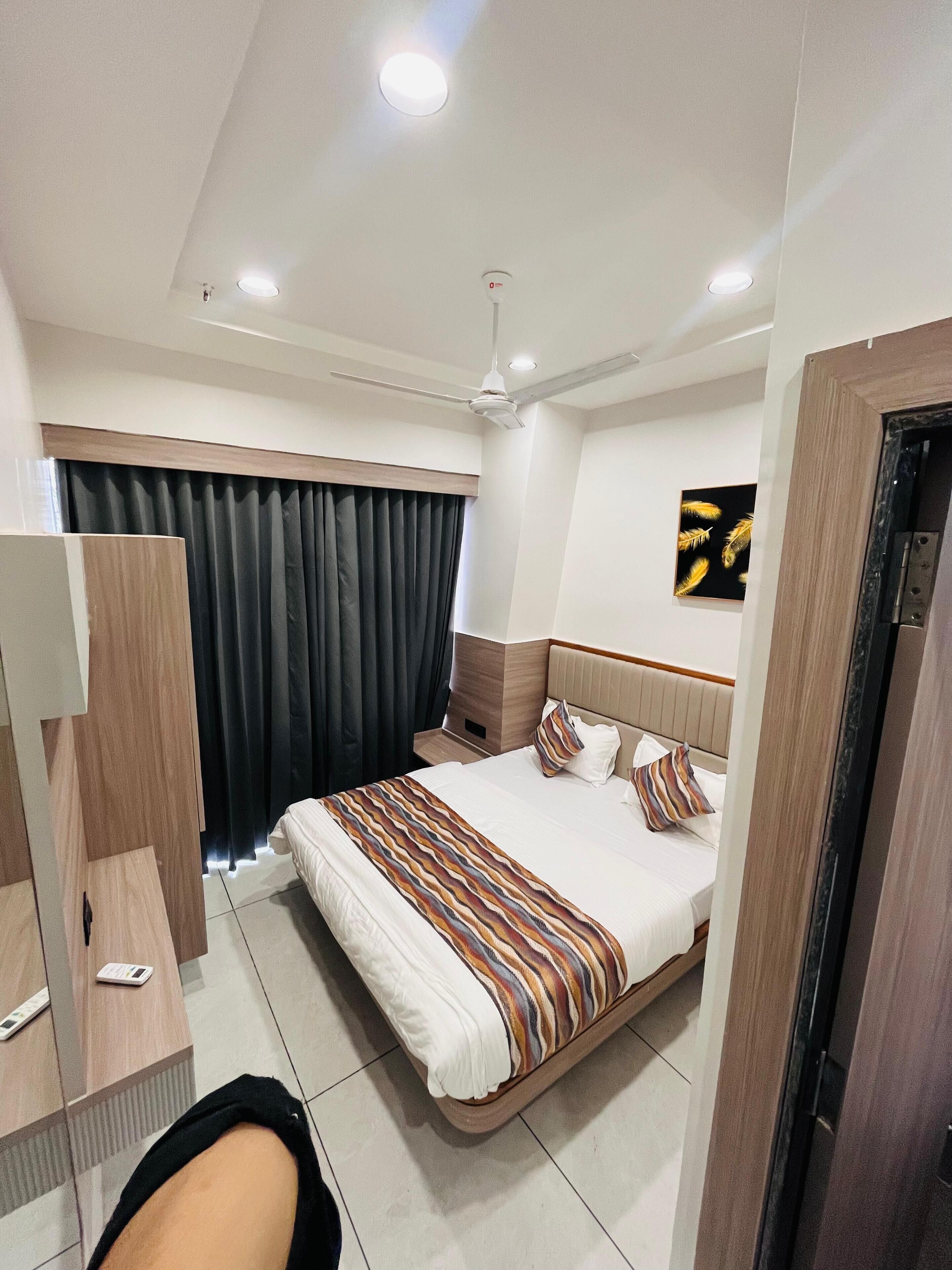 Una habitación de hotel moderna con una cama grande, un escritorio, un armario y un ventilador de techo.