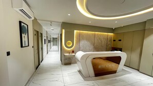 A hotel reception area with a marble floor, a reception desk, and a wall-mounted air conditioning unit.