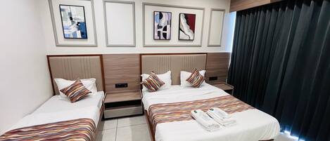 A hotel room with two beds, a ceiling fan, air conditioning unit, and artwork on the wall.