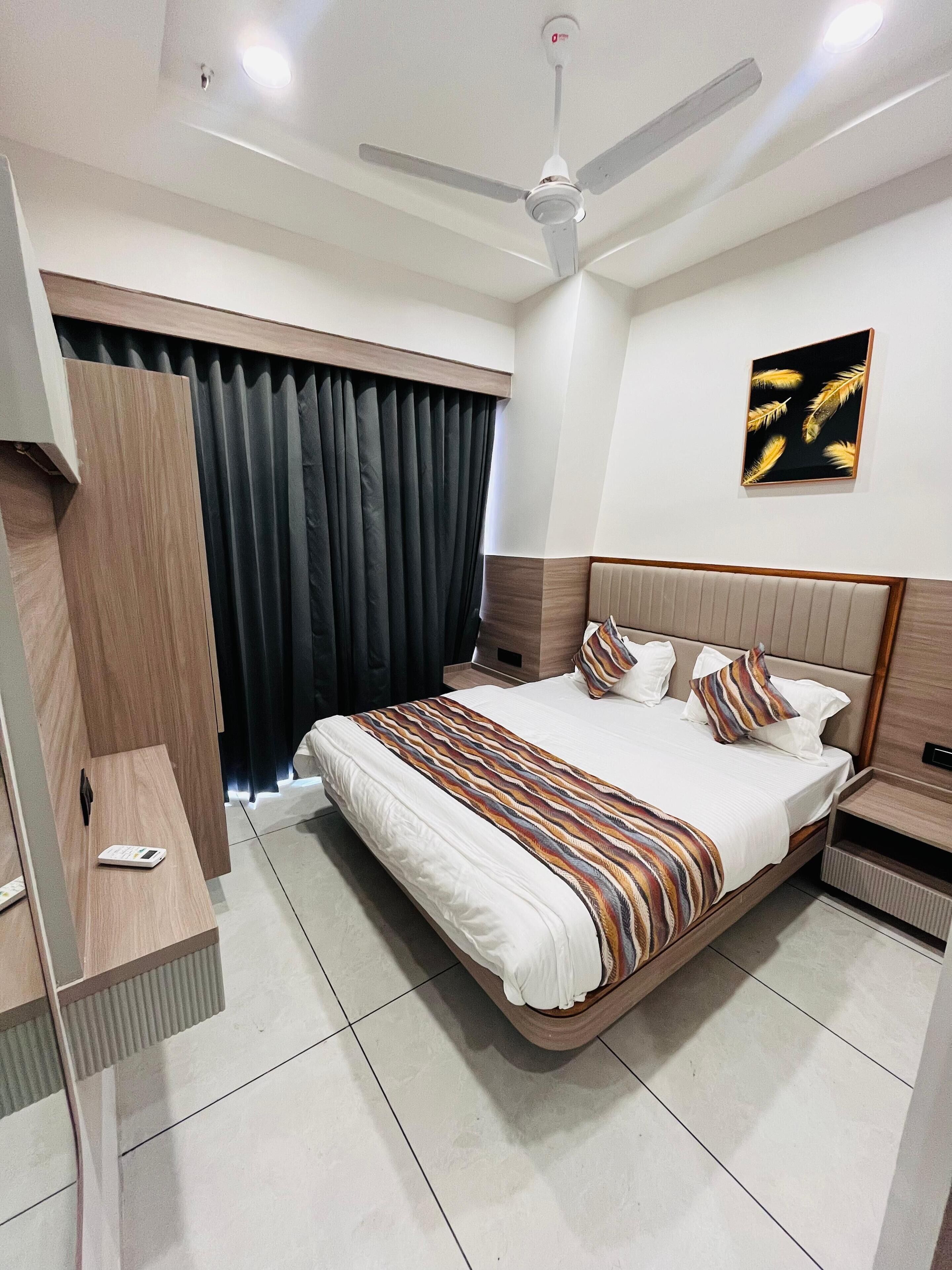 Une chambre d’hôtel moderne avec un grand lit, un bureau, un ventilateur de plafond et un tableau au mur.