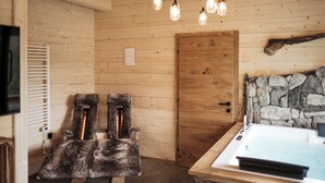 A wooden interior with a stone wall, a wooden door, and a fur-covered chair. - Romantic Chalet Vogelnest | Peace & Comfort in Nature of Franconian Switzerland (Vorra)