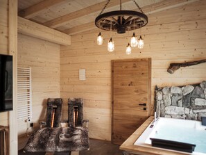 A wooden interior with a stone wall, a wooden door, and a fur-covered chair.