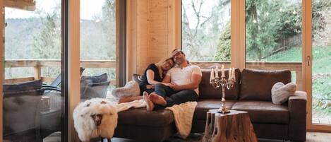 A cozy room with a wooden interior, a large window, and a leather sofa.