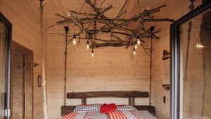 A wooden cabin room with a bed, a rope chandelier, and a wooden headboard. - Romantic Chalet Vogelnest | Peace & Comfort in Nature of Franconian Switzerland (Vorra)