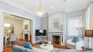 A living room with a television, fireplace, sofa, and dining area. - Charming 2-bedroom flat on Broughton Street, perfect for your getaway! (Savannah)