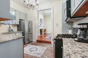 A kitchen with granite countertops, stainless steel appliances, and a patterned rug.
