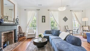 Un salon avec une cheminée, un canapé bleu, une table basse ronde et un lustre.