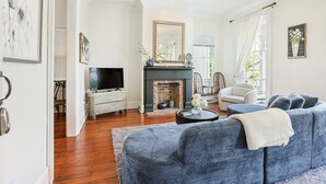 A living room with a fireplace, a sofa, a television, and a coffee table. - Stay on Broughton, Downtown Savannah, Sleeps 10 (Savannah)