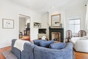 A living room with a fireplace, a television, and a sofa. - Stay on Broughton, Downtown Savannah, Sleeps 10 (Savannah)