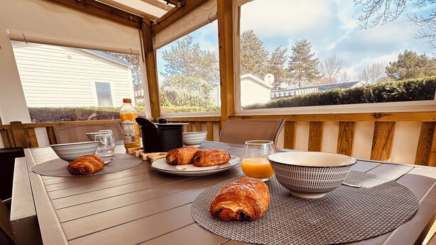 An outdoor dining area with a wooden table, chairs, and a view of the neighborhood. - Mobile home - 2 bedrooms - air conditioning - Enclosed terrace - Locsweethome (Les Mathes)