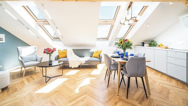 Ein modernes Loft-Apartment mit Dachfenstern, einem Essbereich und einer Küche.