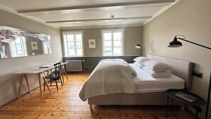 A bedroom with a bed, a desk, and a chair. There are two windows and a radiator. - Gamla Apótekið (The Old Pharmacy)  in heart of Akureyri - South Apartment (Akureyri)