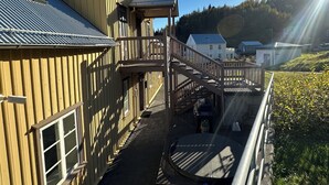 A wooden building with a balcony and a staircase leading to an upper level. - Gamla Apótekið (The Old Pharmacy)  in heart of Akureyri - South Apartment (Akureyri)