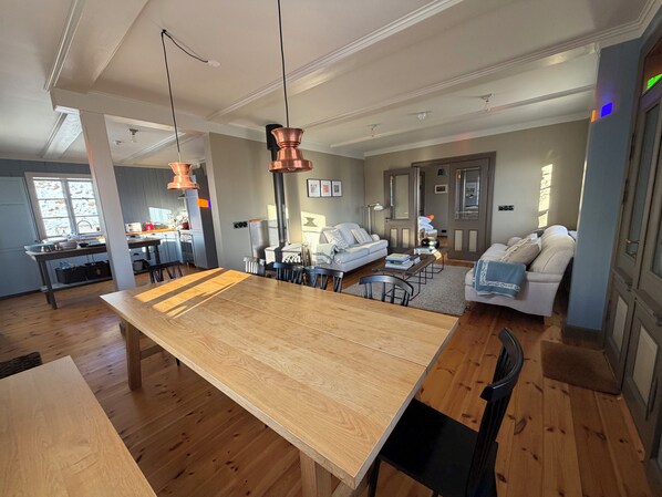 A spacious living area with a large wooden dining table, a sofa, and a fireplace.