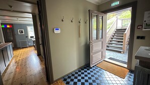 A hallway with a checkered floor, a door leading to a staircase, and a radiator on the wall. - Gamla Apótekið (The Old Pharmacy)  in heart of Akureyri - Main apartment (Akureyri)