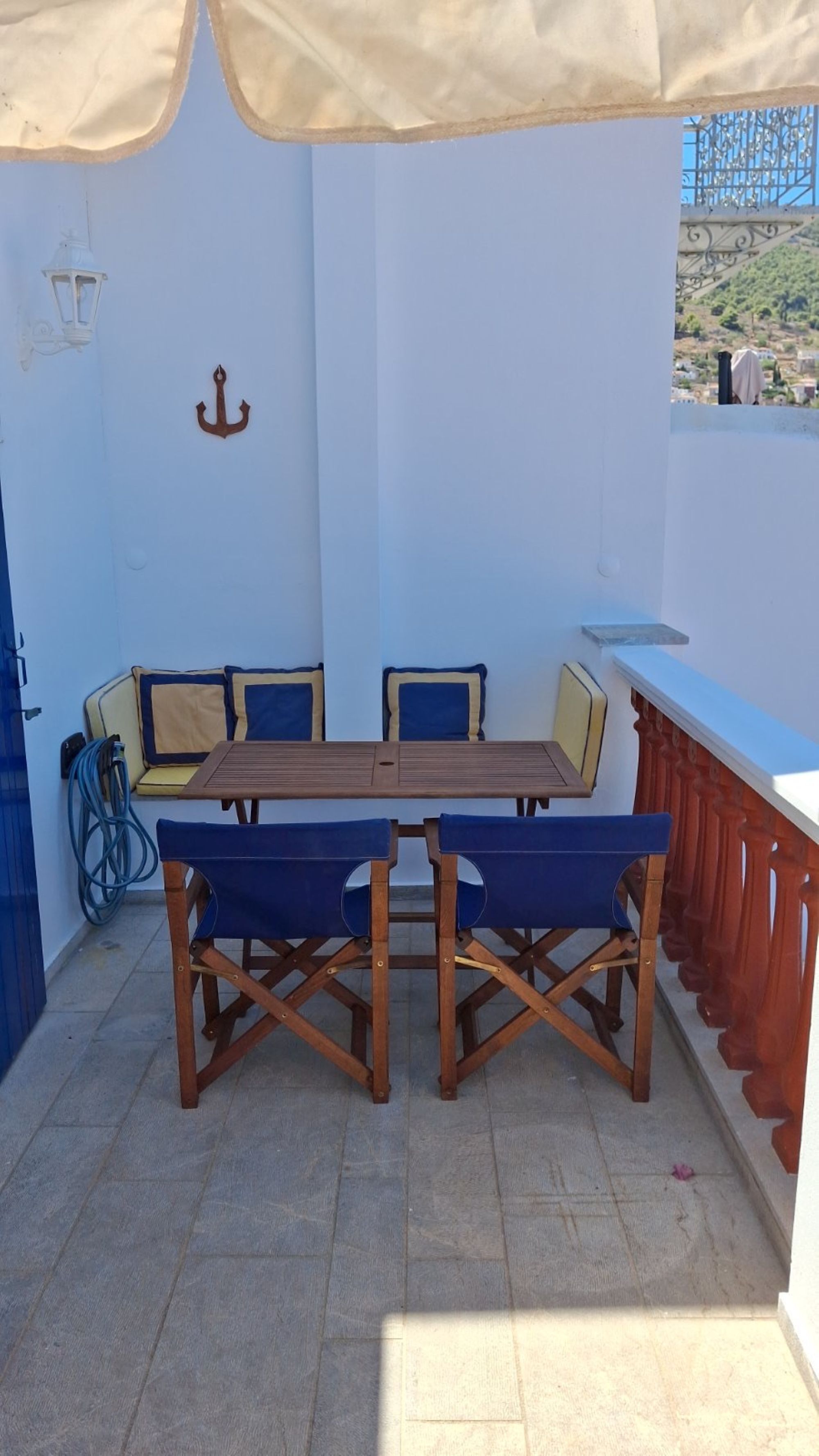 Uma área de refeições ao ar livre coberta, com uma mesa, cadeiras, uma bicicleta e vista para uma encosta.