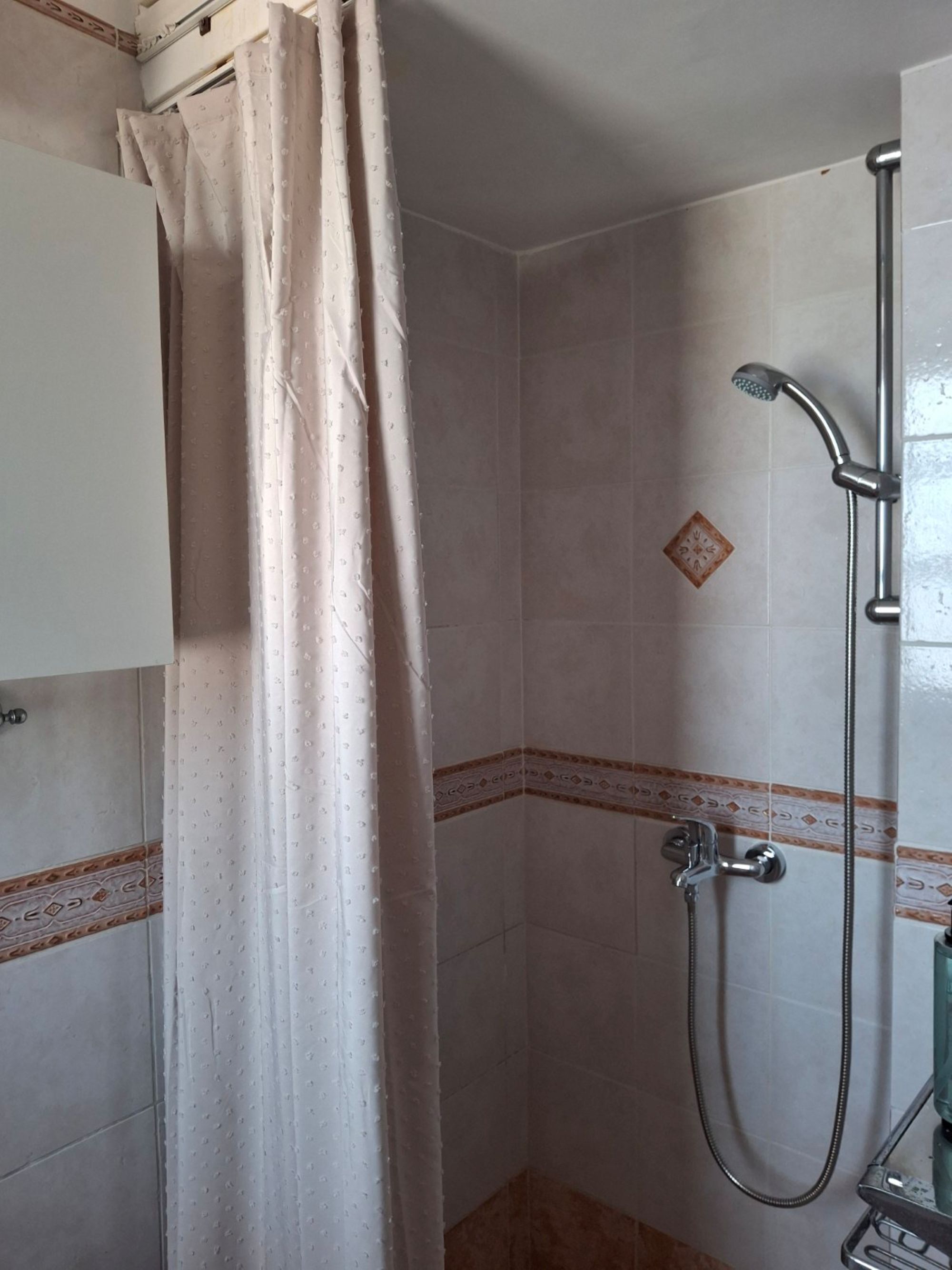 A shower area with a showerhead, a handheld showerhead, and a glass shower tray.