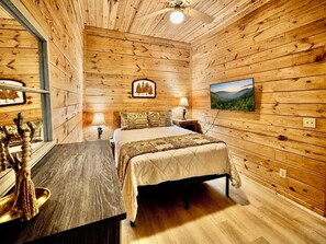 A wooden-paneled room with a bed, bedside lamps, a picture on the wall, and a window.