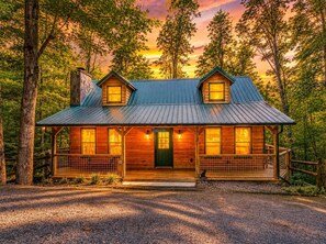 A cabin with a metal roof, wooden walls, and a porch with railings.