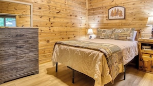 Un dormitorio con paneles de madera, una cama, una mesita de noche, una lámpara y un aparador.
