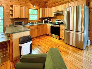 Cocina de cabaña de madera con refrigerador, estufa, microondas y alacenas de madera.