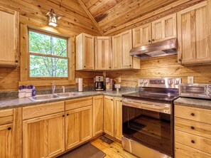 Interno di una baita in legno con cucina, dotata di lavello, fornello e tostapane.
