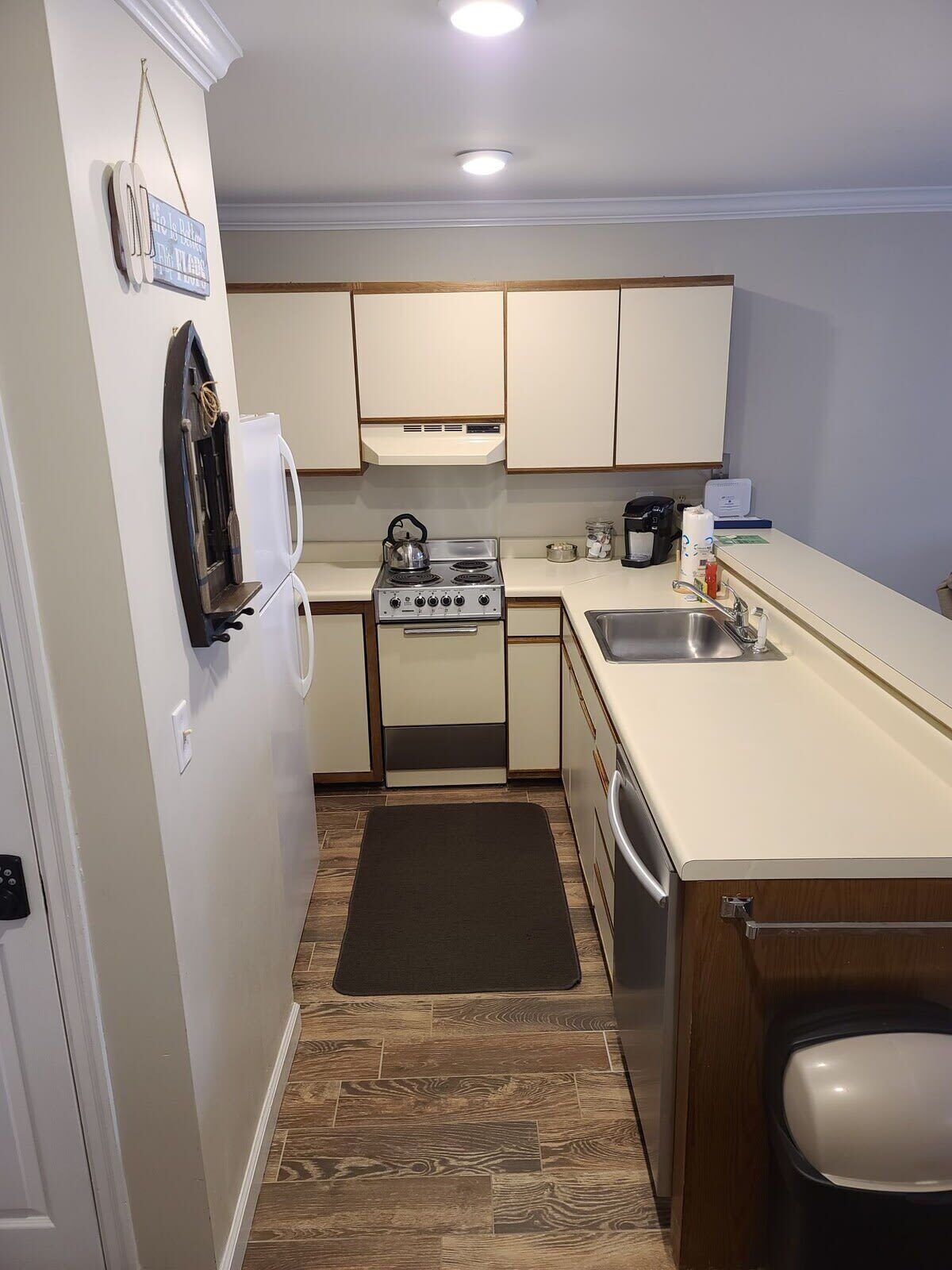 A compact kitchen with white cabinets, a stove, a sink, and a small countertop.