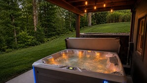 Ett bubbelbad med en kontrollpanel och ett steg för att underlätta insteg, omgivet av en träpergola och utomhusbelysning.
