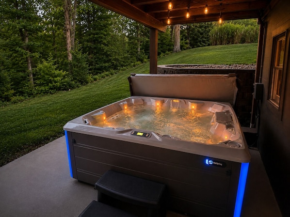 Ein Whirlpool mit Bedienfeld und Einstieg, umgeben von einer Holzpergola und Außenbeleuchtung.