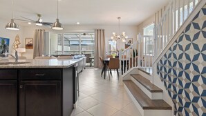 Een moderne keuken met donkere kastjes, een centraal eiland en hanglampen.