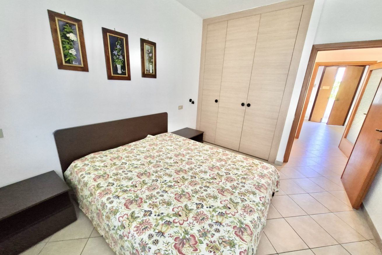 A bedroom with a bed, a wardrobe, and two framed pictures on the wall.