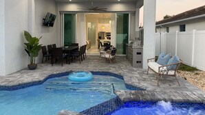 Un patio couvert avec une piscine, un coin repas et une cuisine.