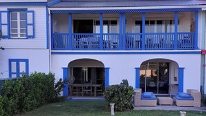 A two-story house with a balcony, a covered porch, and outdoor seating. - Orient blue garden, direct access 50m from the beach! (Baie orientale)