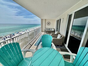 En balkon med udsigt over stranden, udendørs møbler og en sofa.