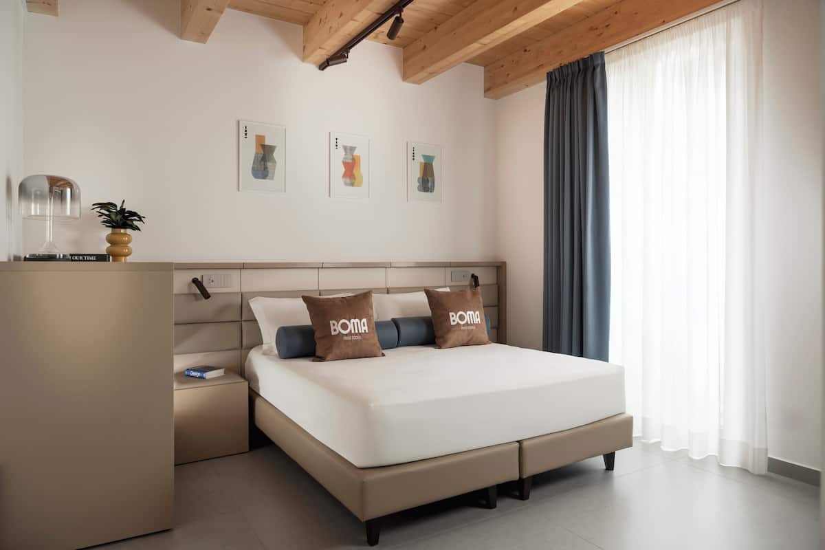 Een moderne slaapkamer met een bed, nachtkastjes, een lamp en kunst aan de muur.