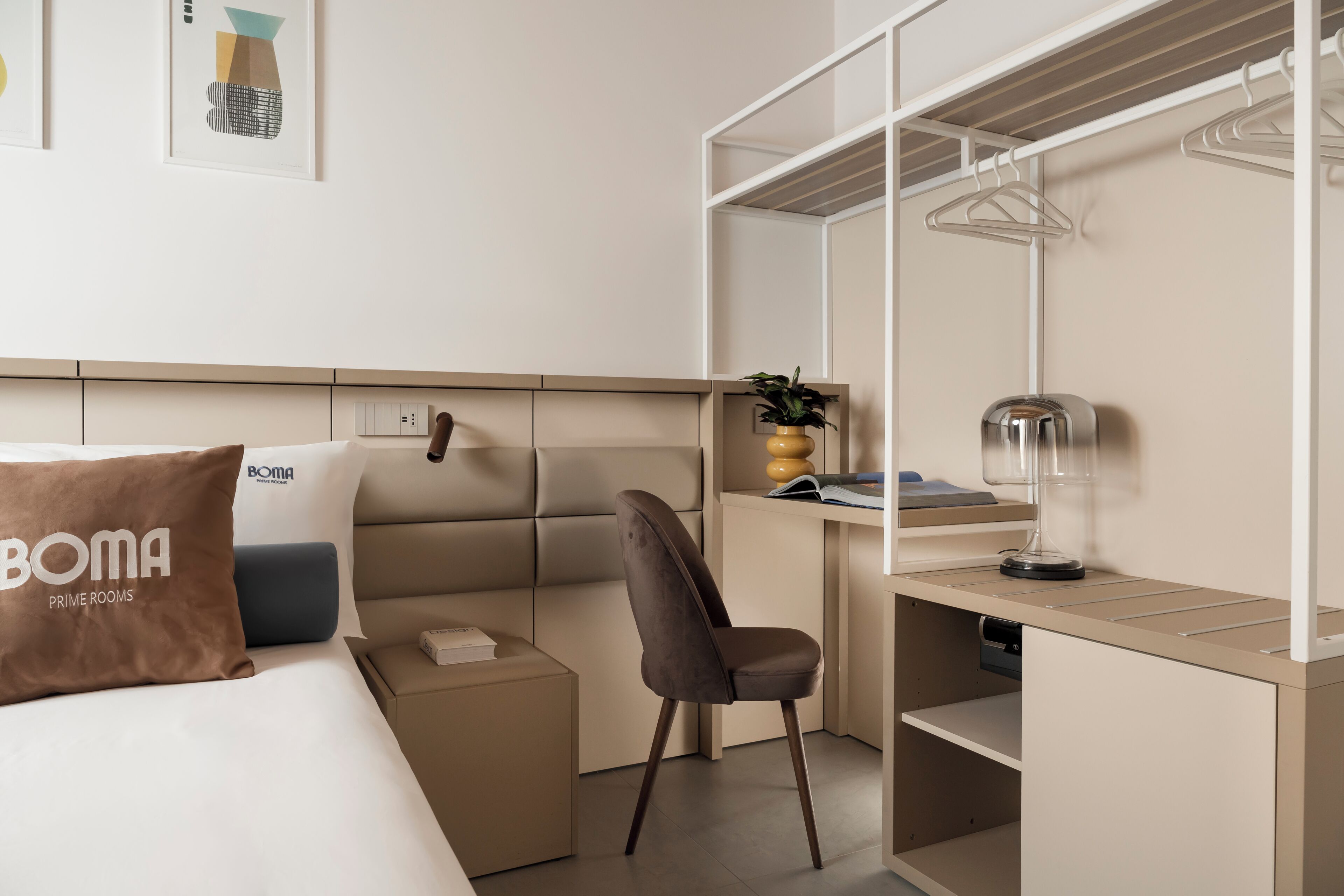A hotel room with a bed, a desk, a chair, a wardrobe, and a bedside table.