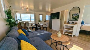 Un salon moderne avec un canapé, une table à manger et un téléviseur fixé au mur.