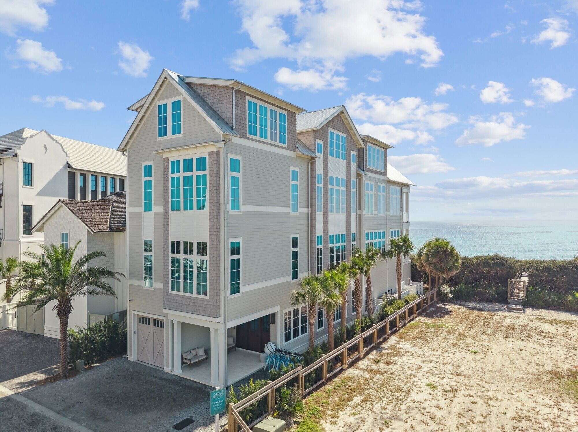 A multi-story beachfront property with a covered patio, a pool, and a view of the ocean.