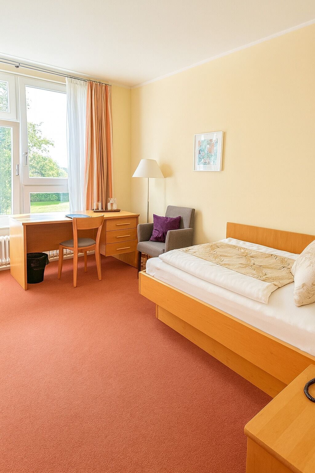 Ein Schlafzimmer mit Bett, Schreibtisch, Stuhl, Lampe und Heizkörper.