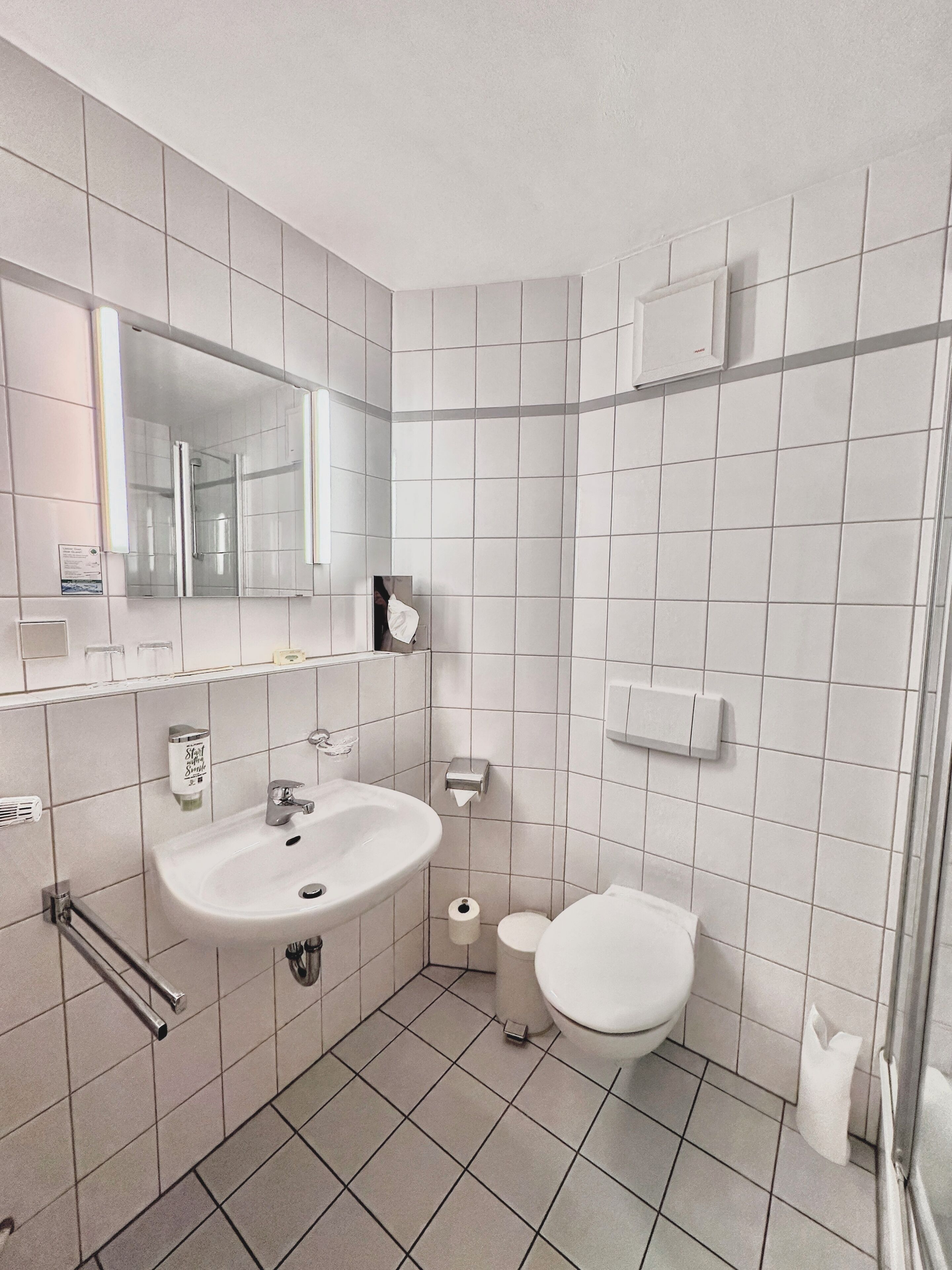A modern bathroom with a white sink, mirror, and toilet.