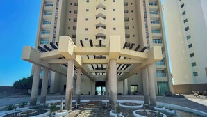 A multi-story building with a central atrium, columns, and a landscaped courtyard with planters. - Tranquil Beachfront Condo 2BR Family Retreat (Puerto Peñasco)